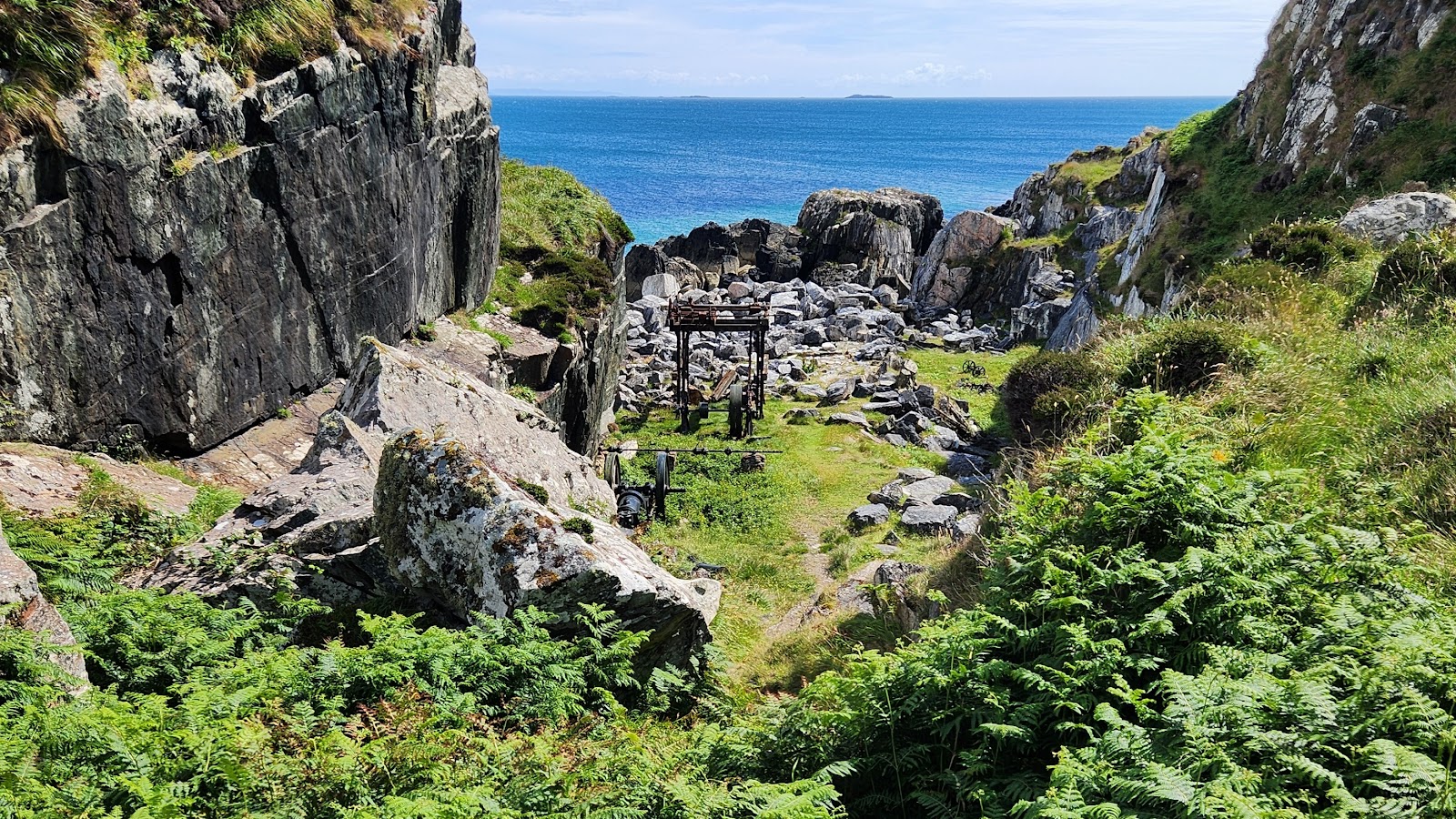 The rocky inlet of the marble quarry on Iona, green slopes above the blue sea.