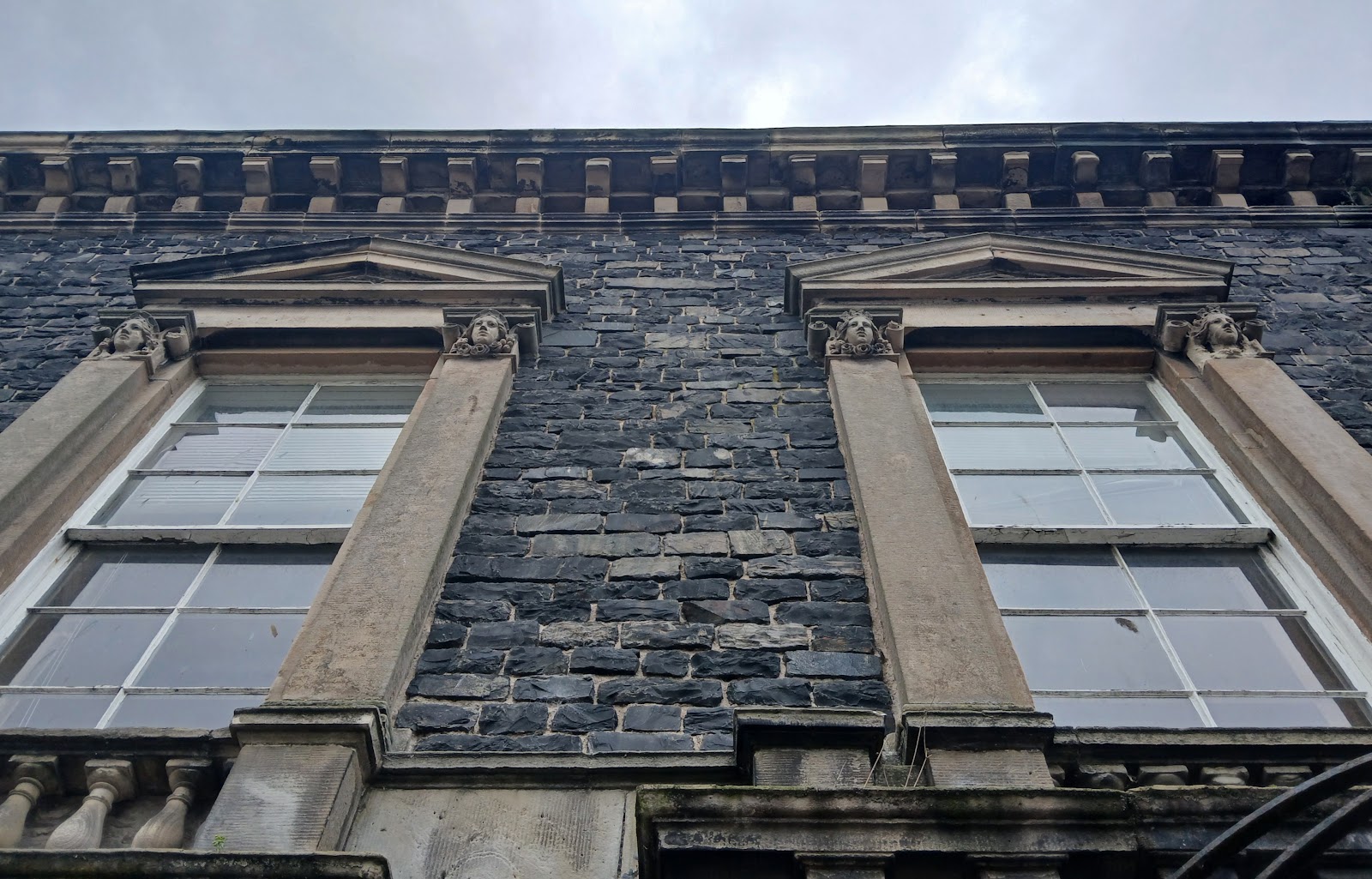 The stone front of an old Banff building, its tall windows with carved surrounds.