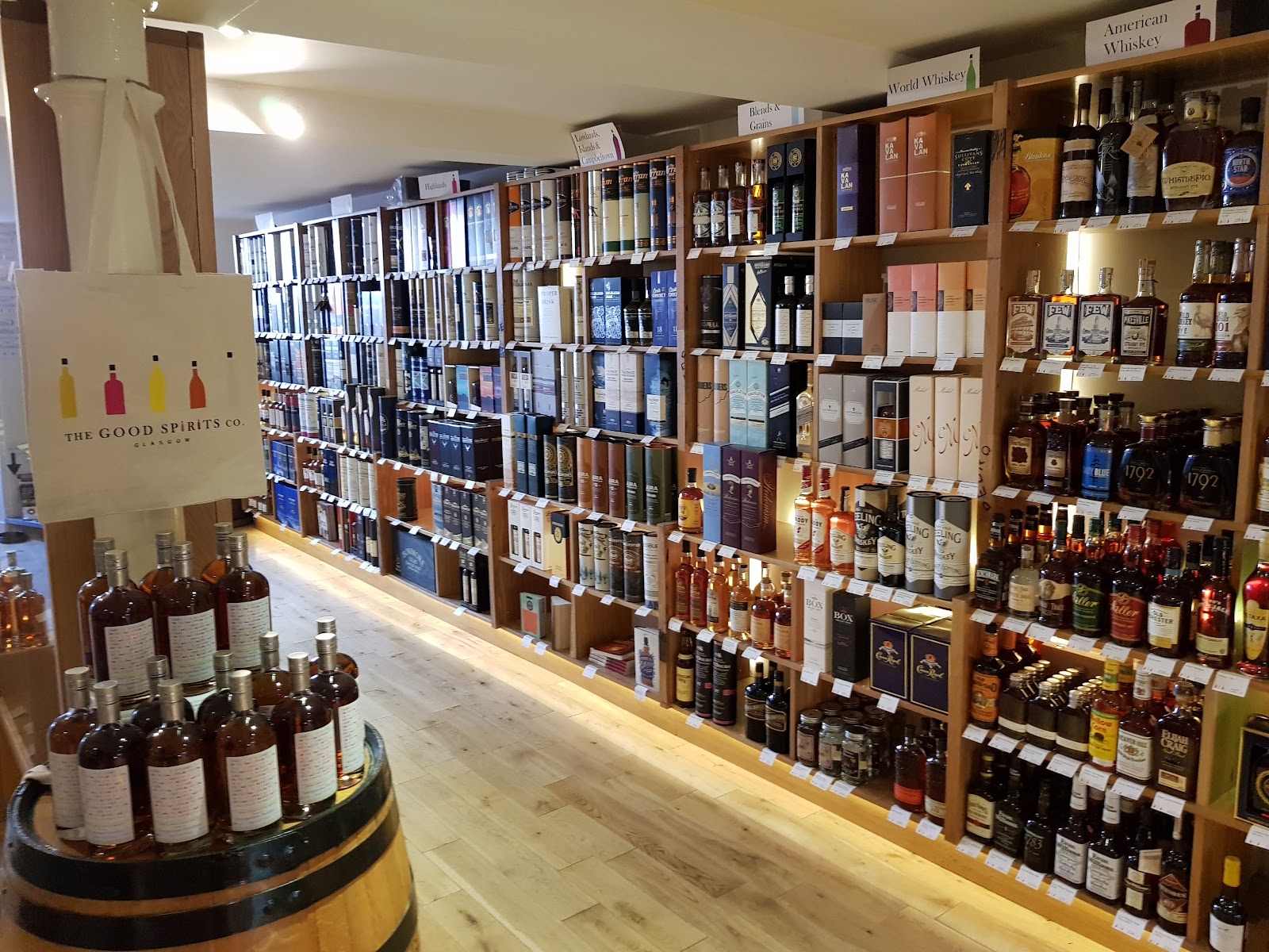 Wooden shelves of whisky and spirits running the length of the Good Spirits Co. on Bath Street, with a barrel of bottles in the front.