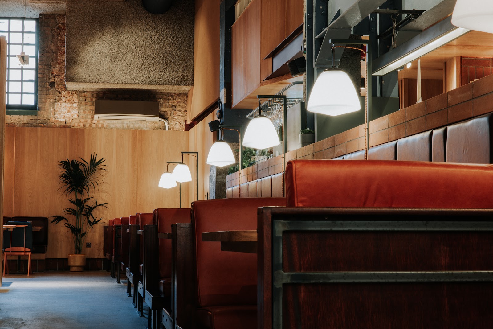 Red leather booths, globe lamps and timber walls in the dining room at Margo.