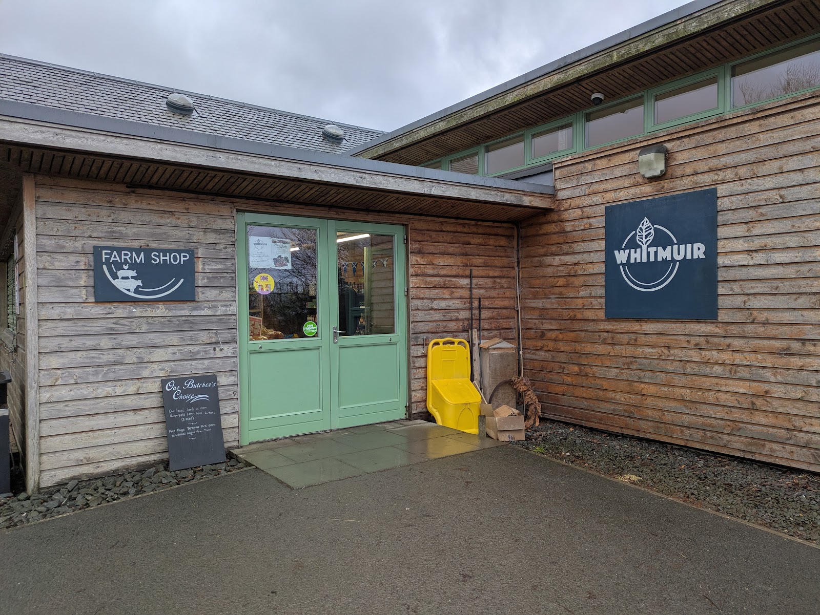 The farm shop door at Whitmuir, between its Farm Shop and Whitmuir signs on the timber wall.