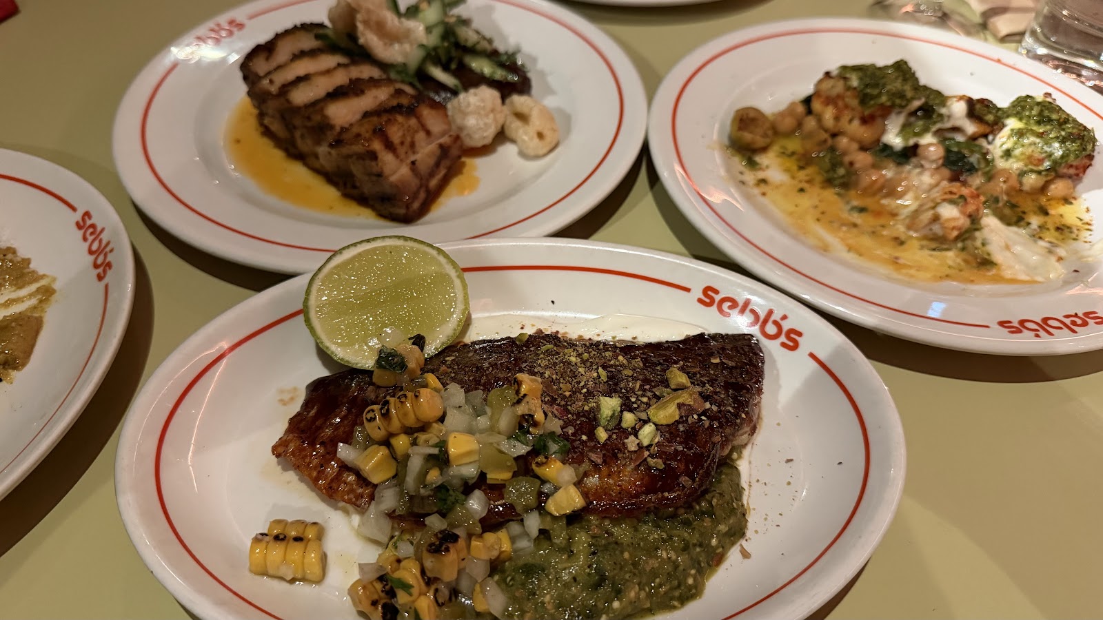 Sea bream with charred corn and tomatillo salsa, pork belly and prawns with chickpeas on Sebb's red-rimmed plates.