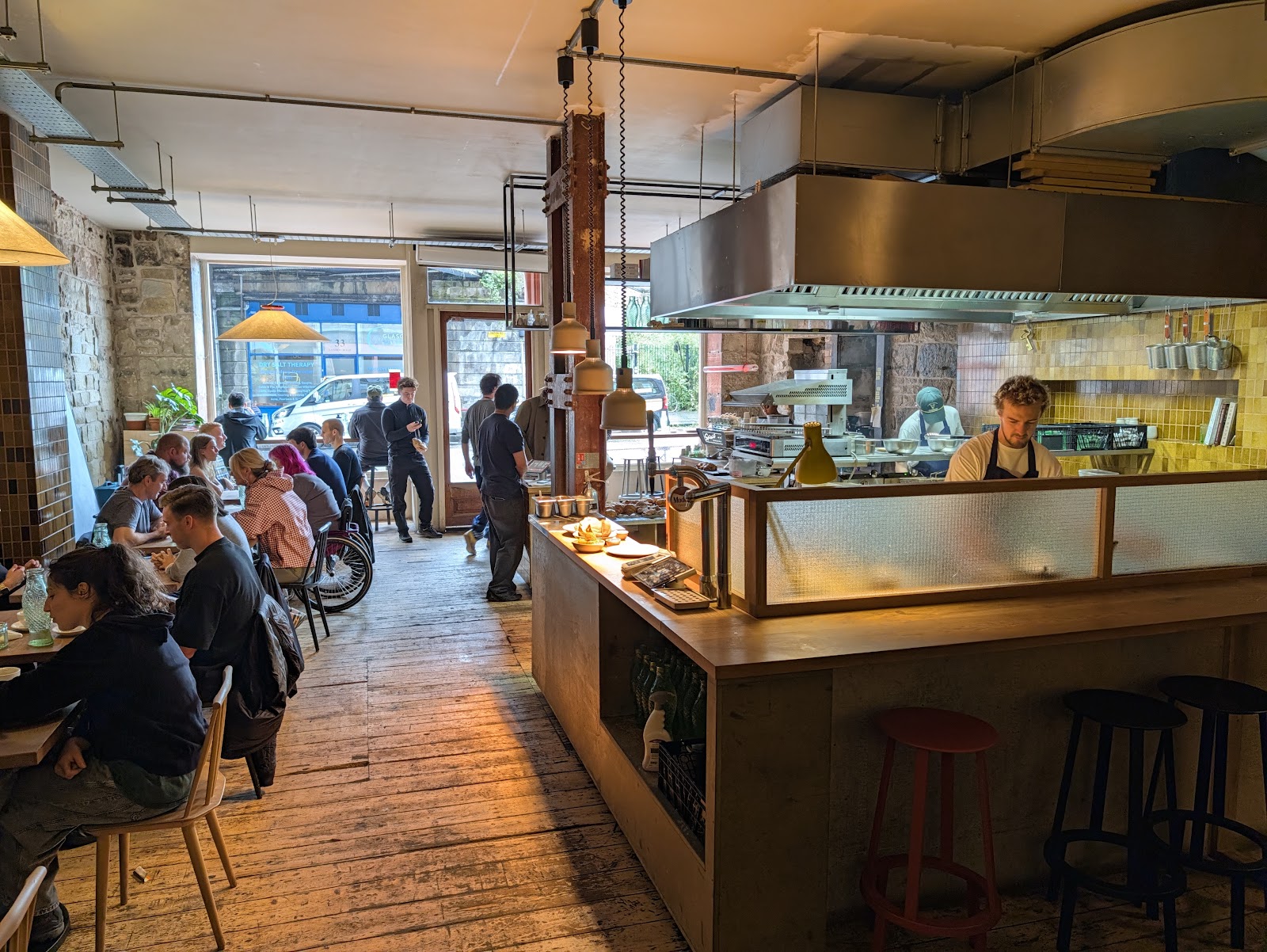 The long room at Outlier, with tables down one side and the open kitchen and counter on the other.