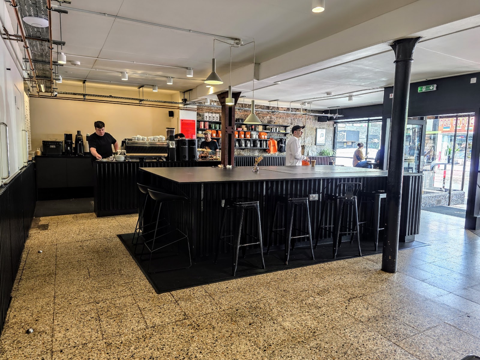 The central bar with stools on a terrazzo floor.