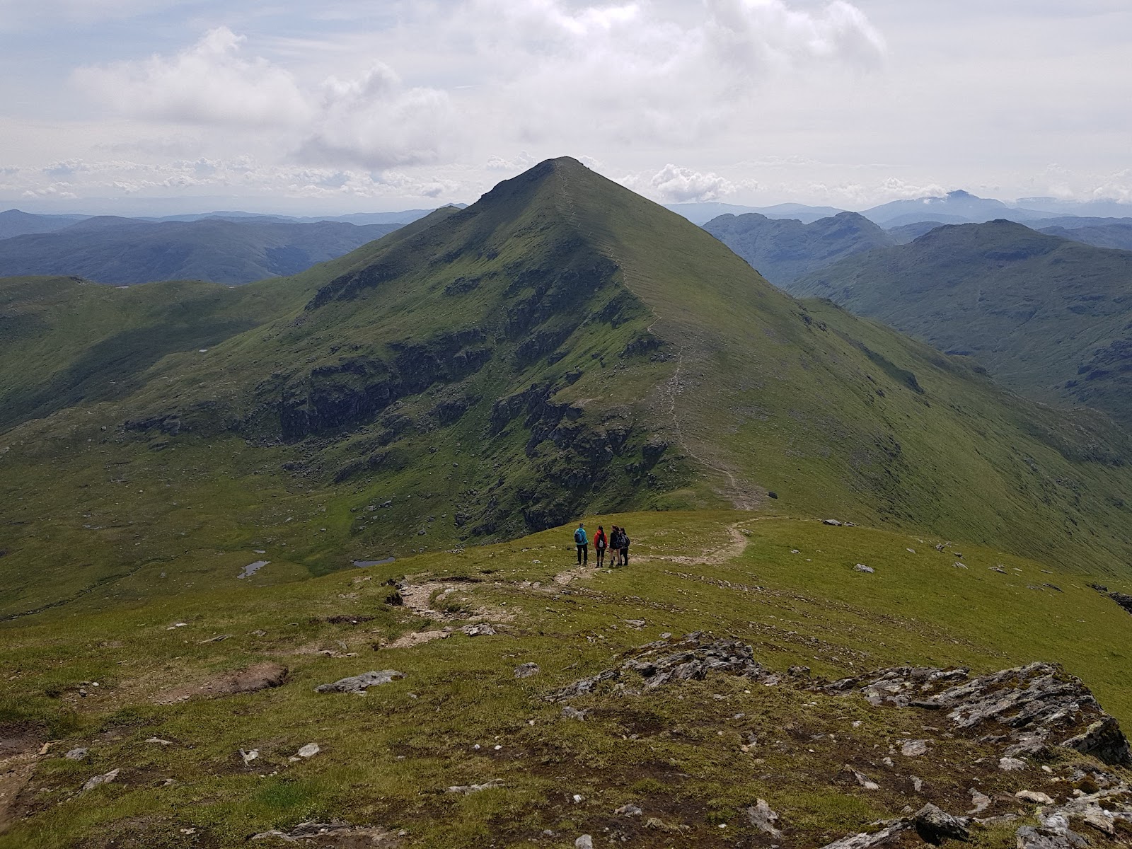 Walkers on the green ridge high on the hill.