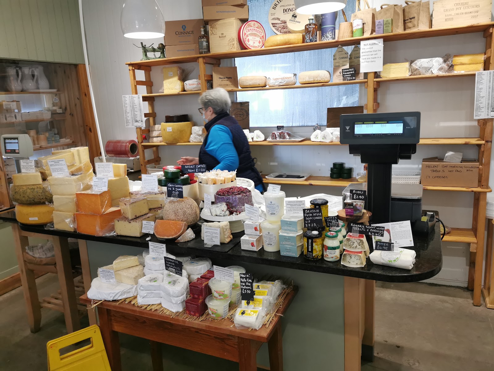 The cheese counter in the Cheese Pantry at Connage Highland Dairy, with whole cheeses on the shelves behind.