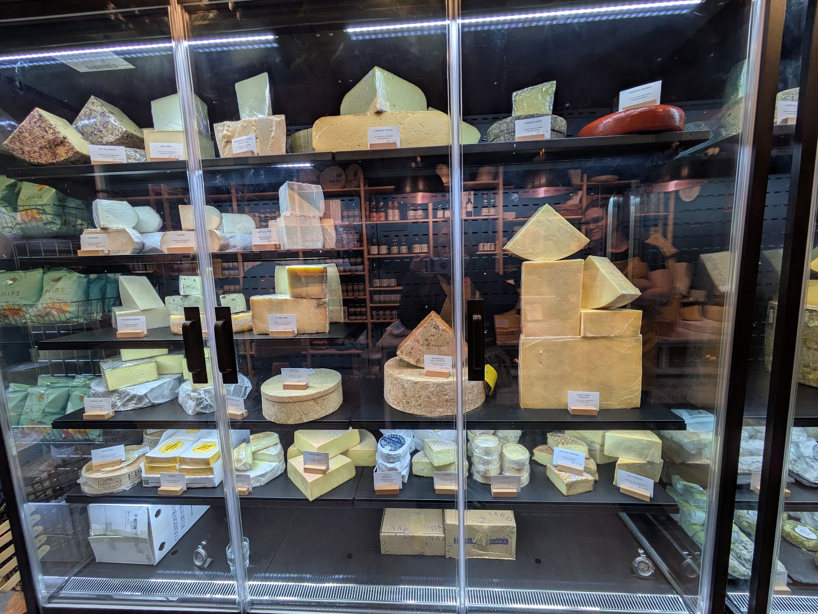 The Cheese Gallery at The Big Cheese on Broughton Street: glass cabinets of cut wedges and whole wheels of cheese, each with its label.