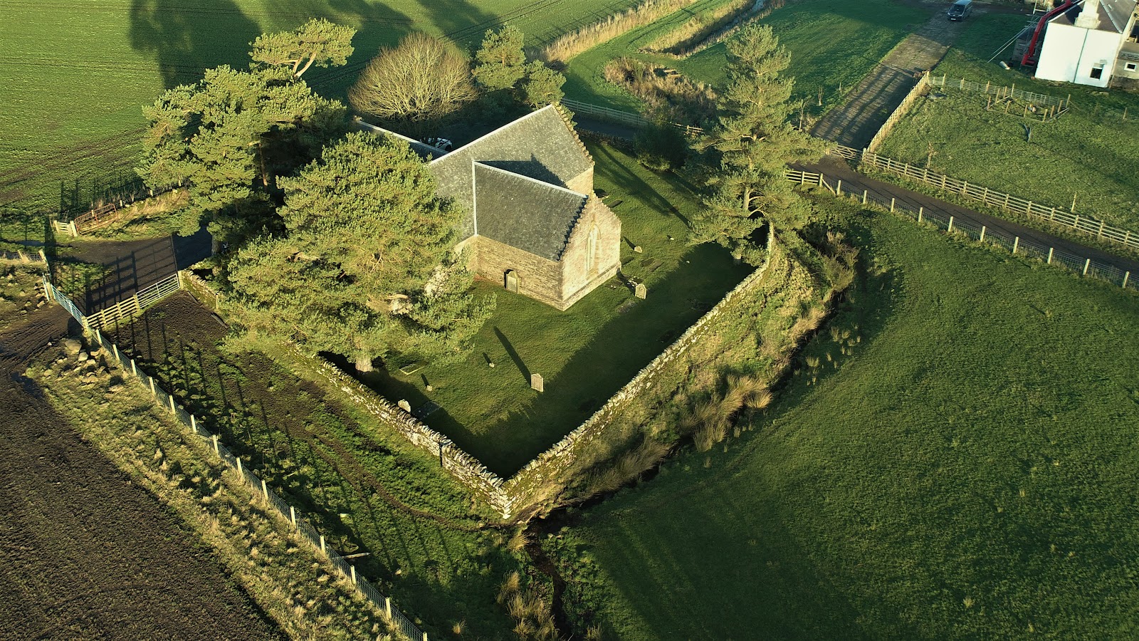 Tullibardine Chapel from the air, among trees in its walled churchyard.