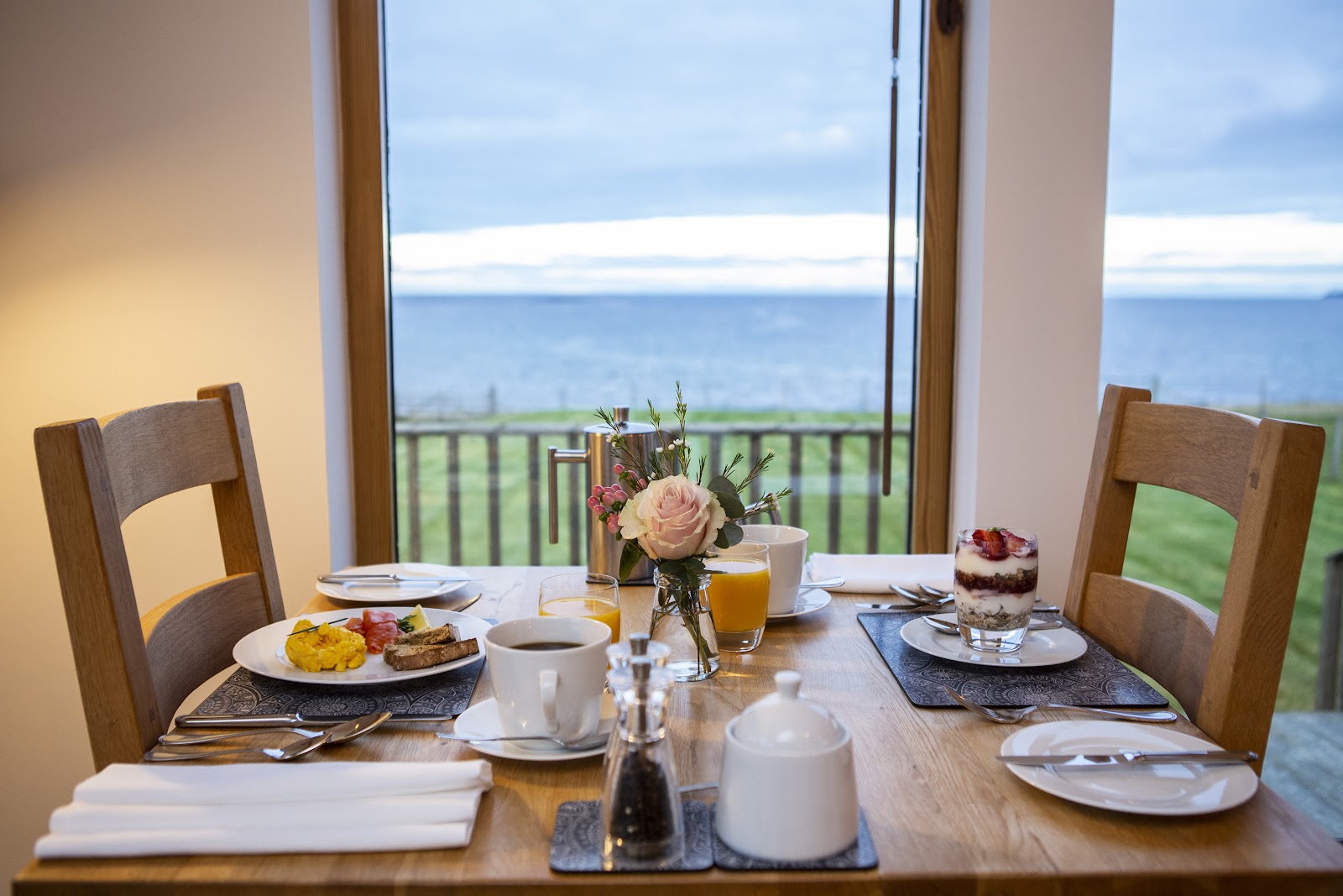 Breakfast laid on a table by a tall window at Broad Bay House, the sea and the far shore beyond the balcony.