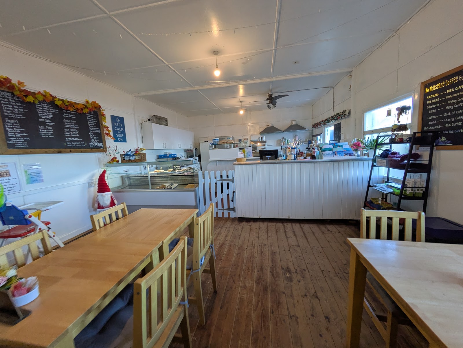 Inside the beach café: wooden floor and tables, with chalkboard menus above the white counter.