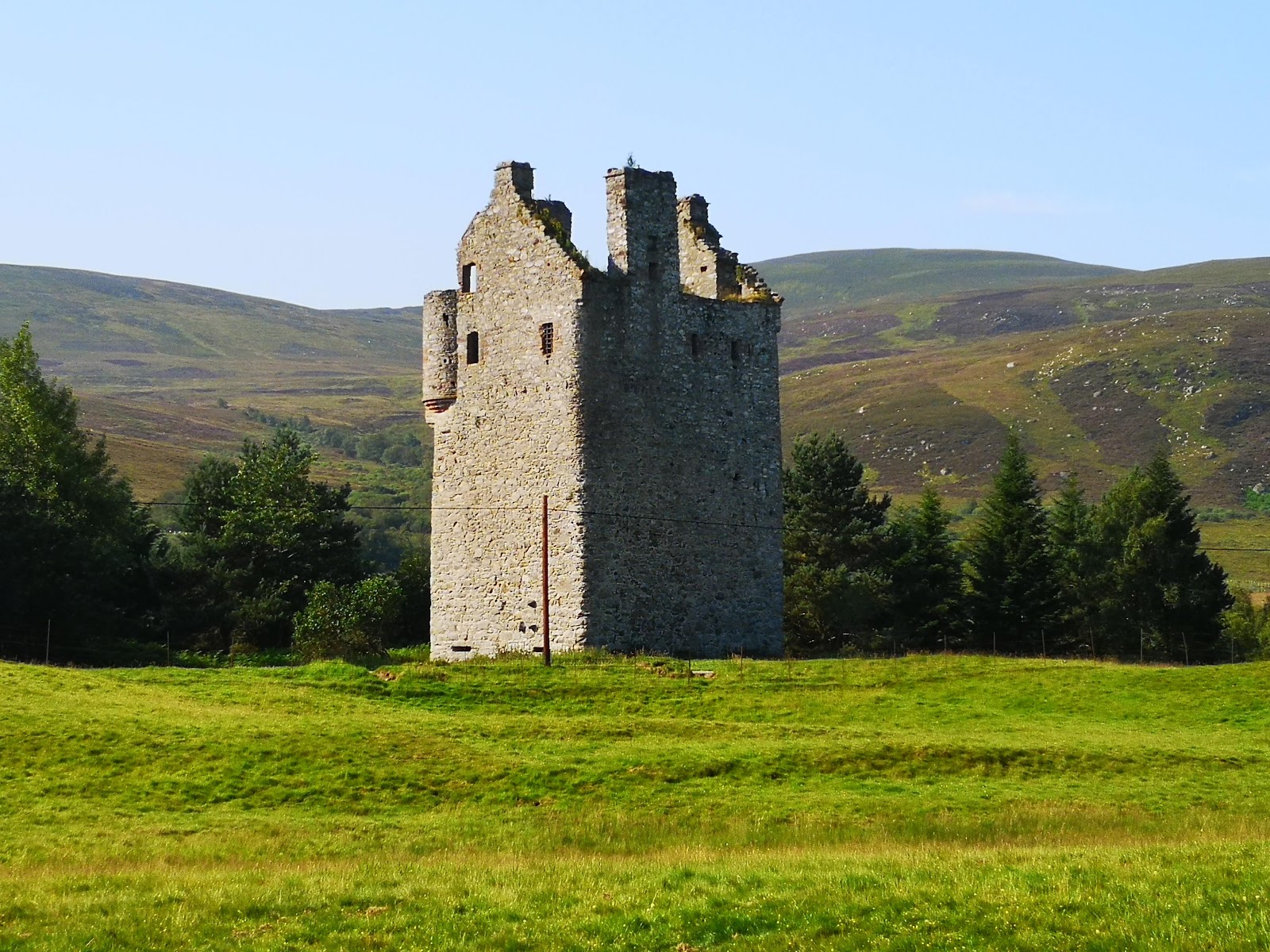 The tall ruined tower of Invermark Castle among fields at the head of Glen Esk.