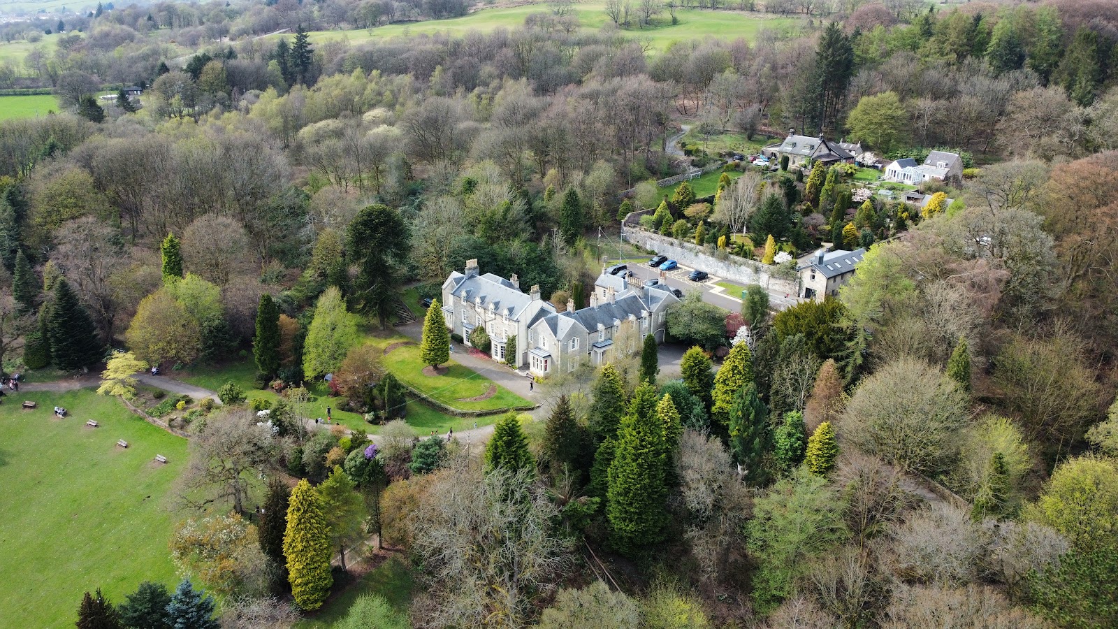Colzium House from the air in spring, its grey stone front among lawns, conifers and woods at the east end of Kilsyth.