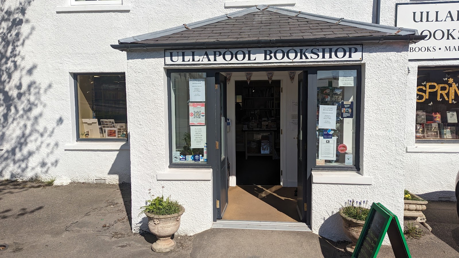 The Ullapool Bookshop's white frontage and porch on Quay Street, its windows full of books.