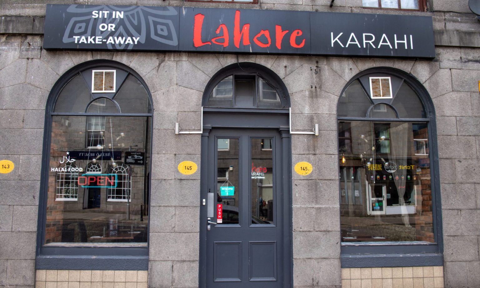 Lahore Karahi's front at 145 King Street: a black sign with the name in red over three arched windows in a granite wall.
