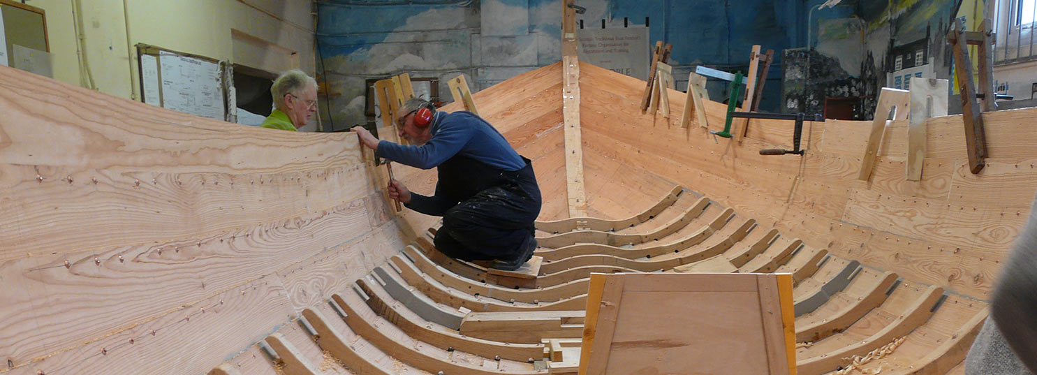 A volunteer shaping a timber boat in the Boatshed at Portsoy.