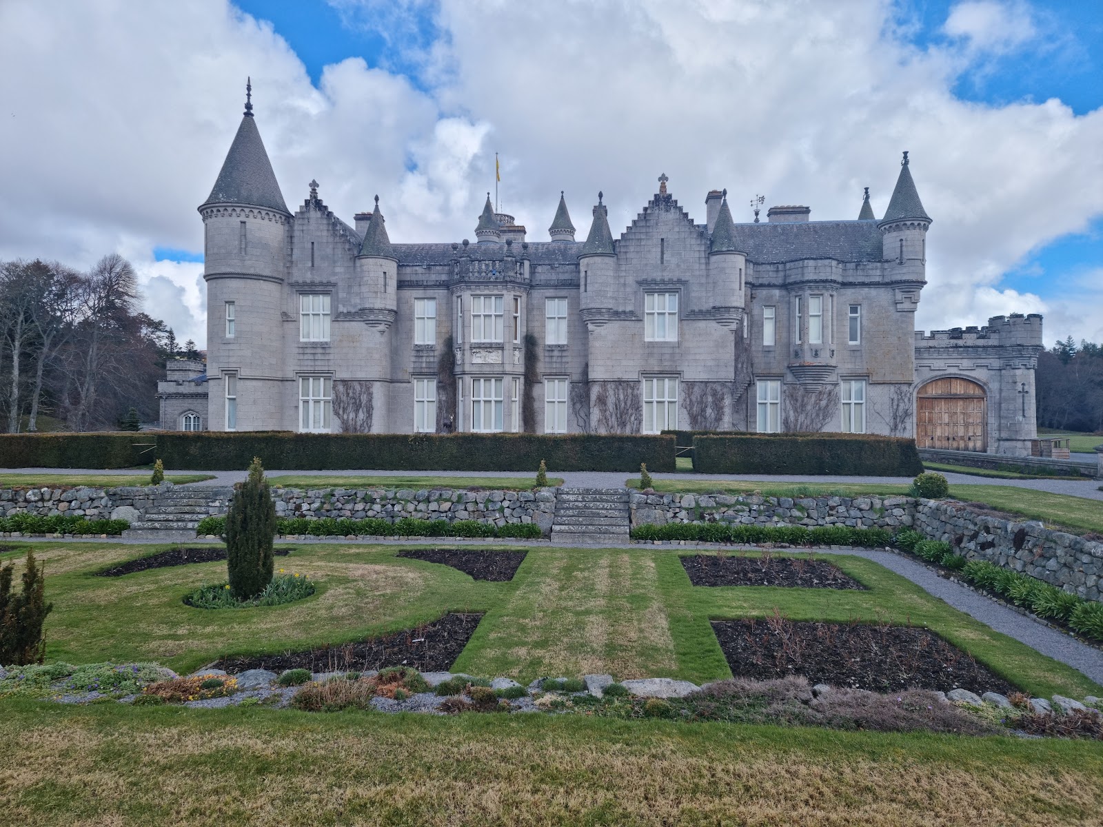 Balmoral Castle beyond its formal garden under a blue sky.