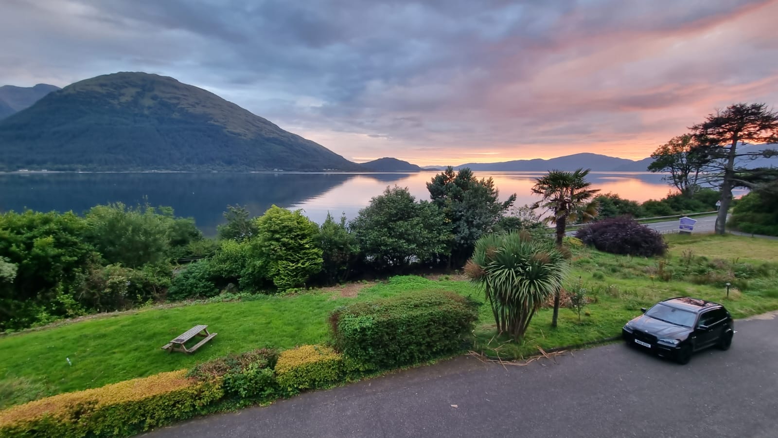 Sunset over Loch Linnhe from the hotel's garden, a dark mountain against a pink sky and the loch still below.