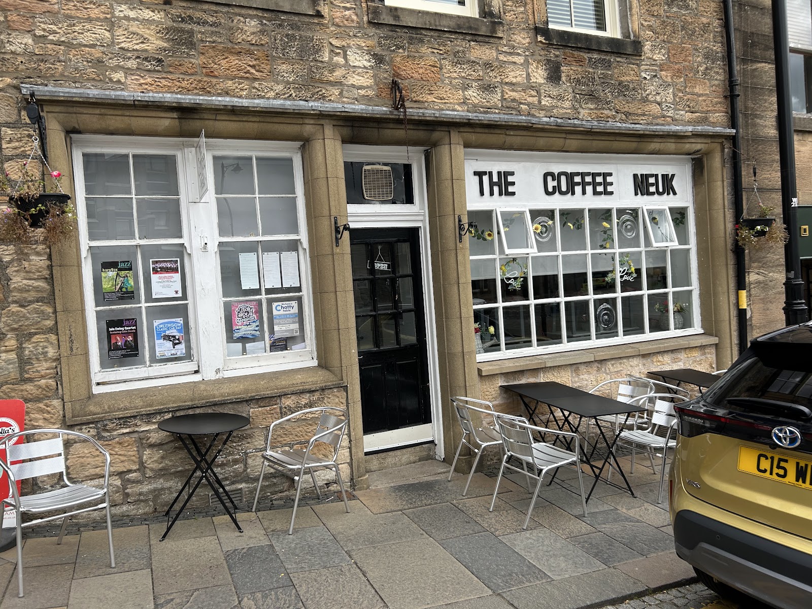The Coffee Neuk at Linlithgow Cross, a stone shopfront with small-paned windows and tables outside.
