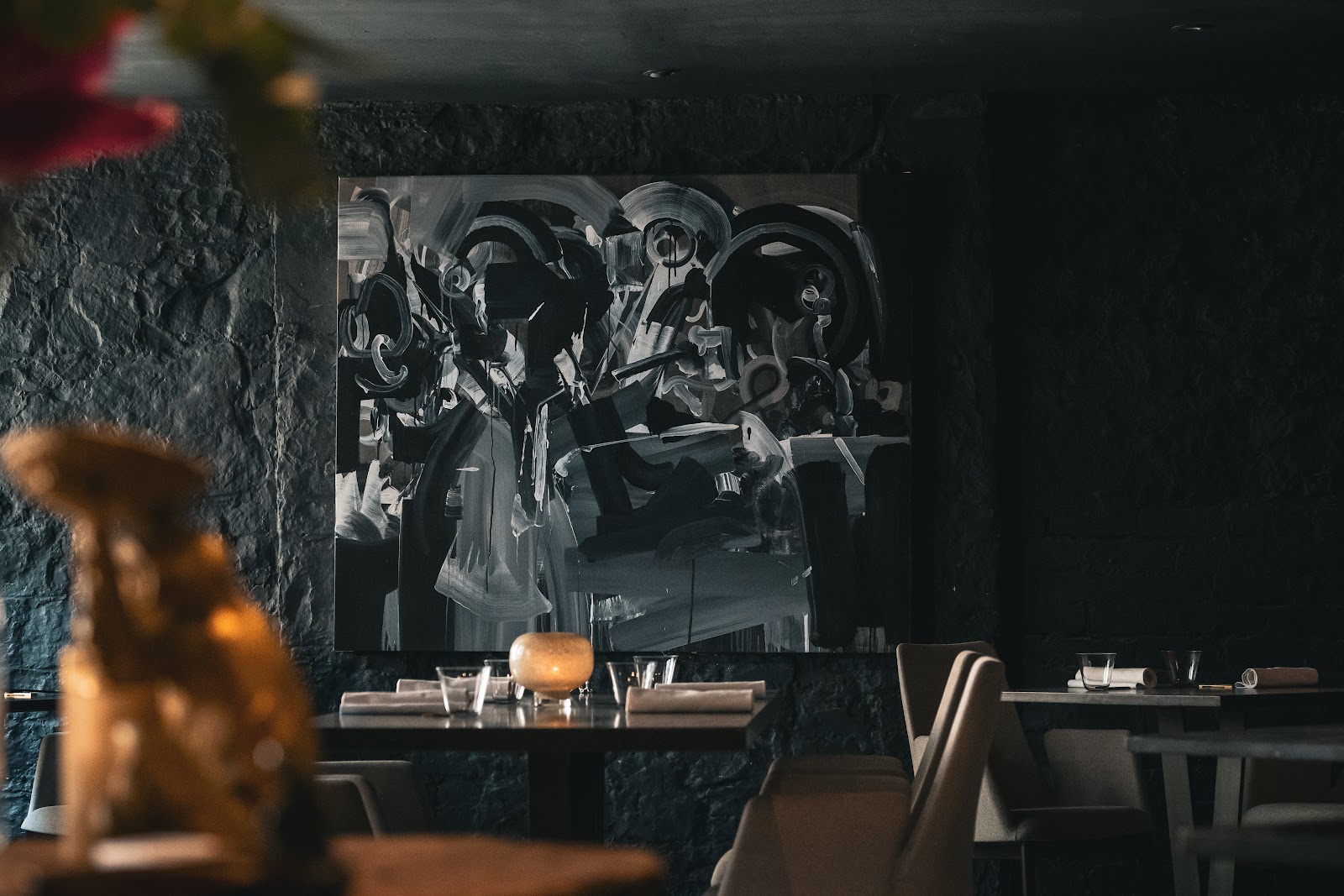 Avery's dining room in Stockbridge, with dark stone walls, a large black and white painting and candlelit tables laid with linen napkins.