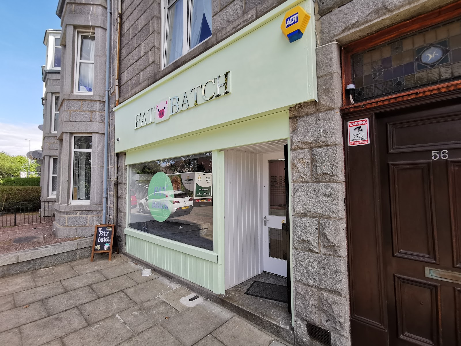 Fat Batch on Elmbank Terrace on a sunny day: a pale green shopfront with a pig between the words of its name, set into a granite tenement.