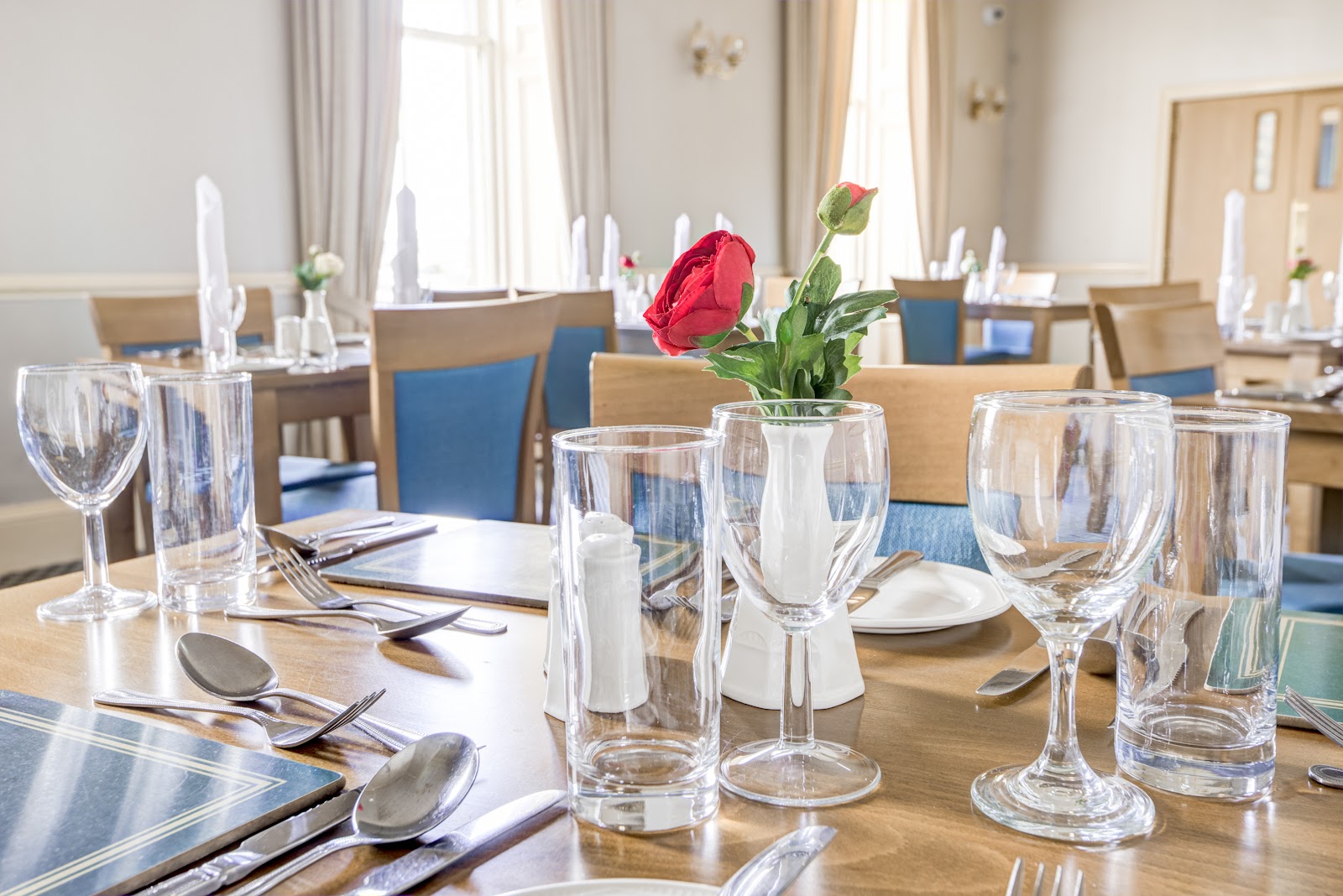 The bright dining room of the No 1 Bistro in Wick, tables laid with glasses and a red rose in a vase.