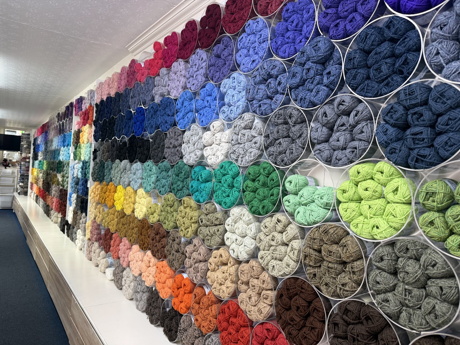 The yarn wall at Jamieson's of Shetland in Lerwick, balls of Shetland wool in every colour stacked in round clear tubes along the length of the shop.