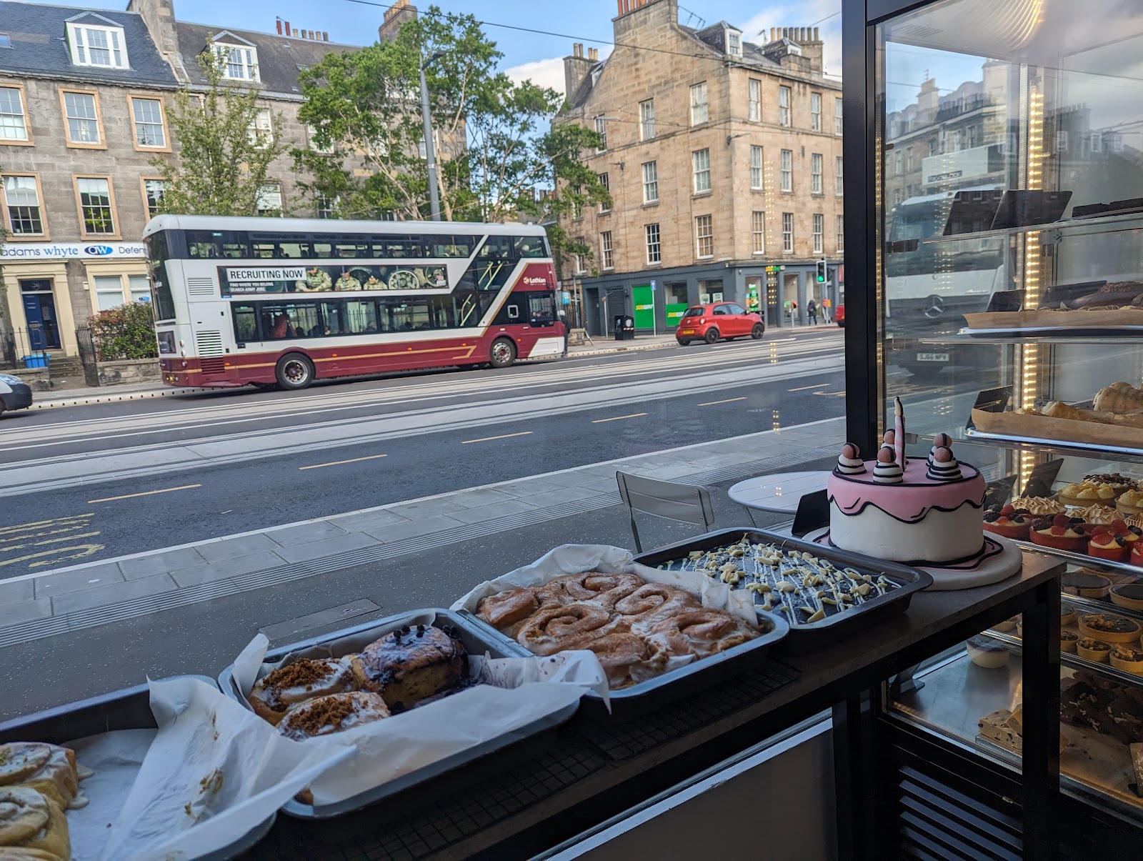 Buns and bakes on the window counter at Krema Bakehouse, looking out over Leith Walk with a bus passing on the far side.