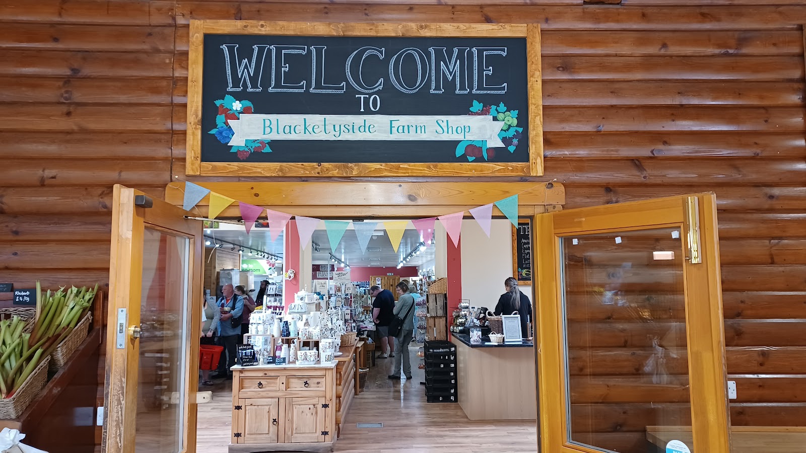 The painted Welcome to Blacketyside Farm Shop sign over the open doors, with shelves of gifts and the counter inside.