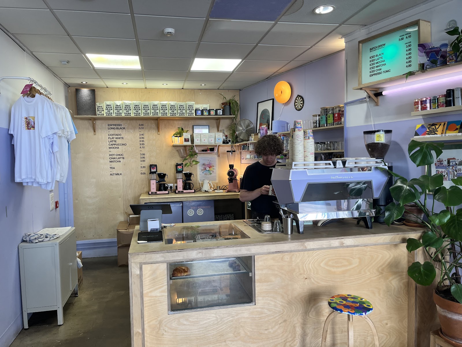 The counter at EH9 Espresso on the Perth Road, Dundee, with a barista at the coffee machine and the price list on a plywood wall.