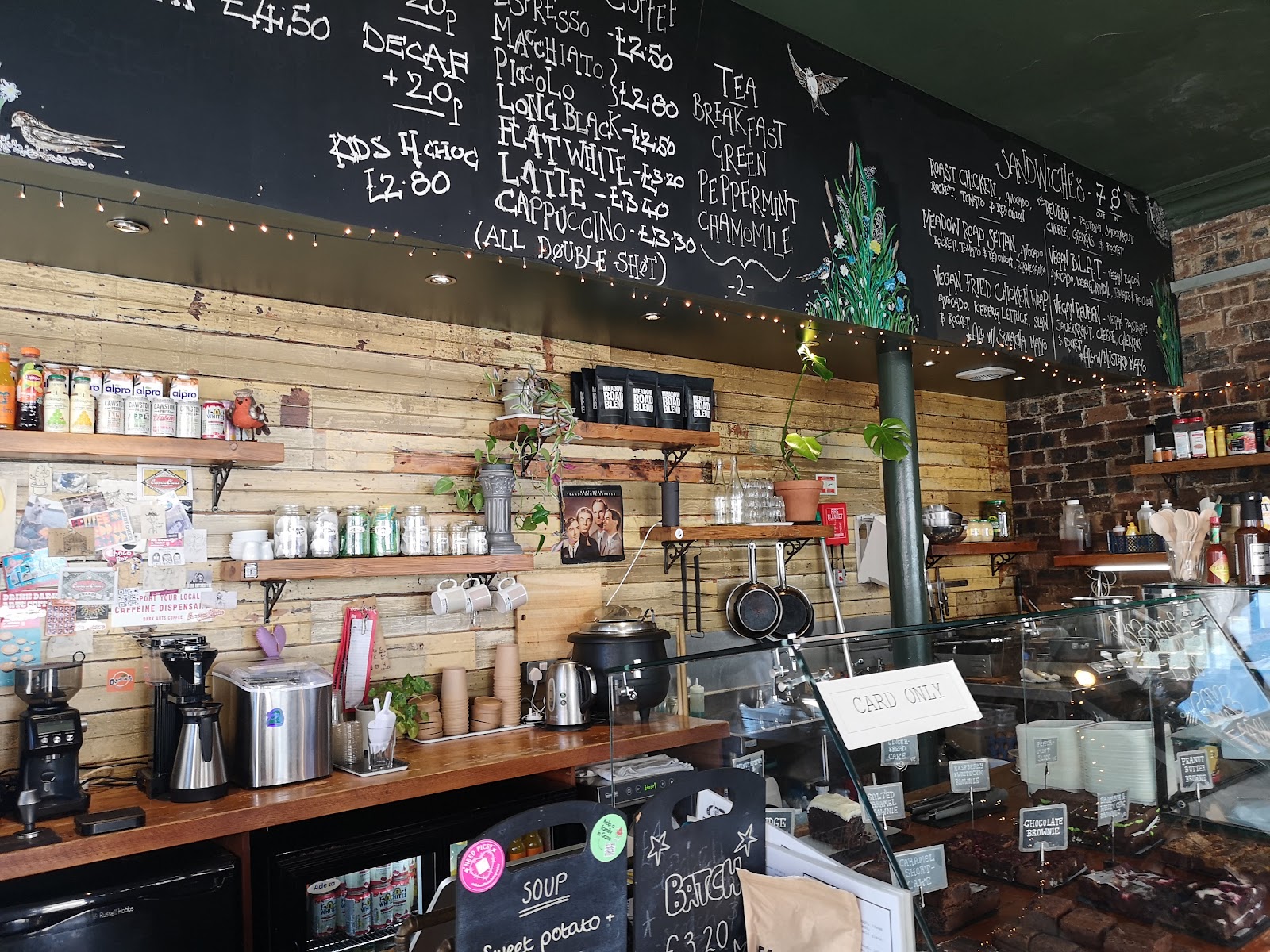 The counter under a chalkboard wall, jars and bottles on shelves.