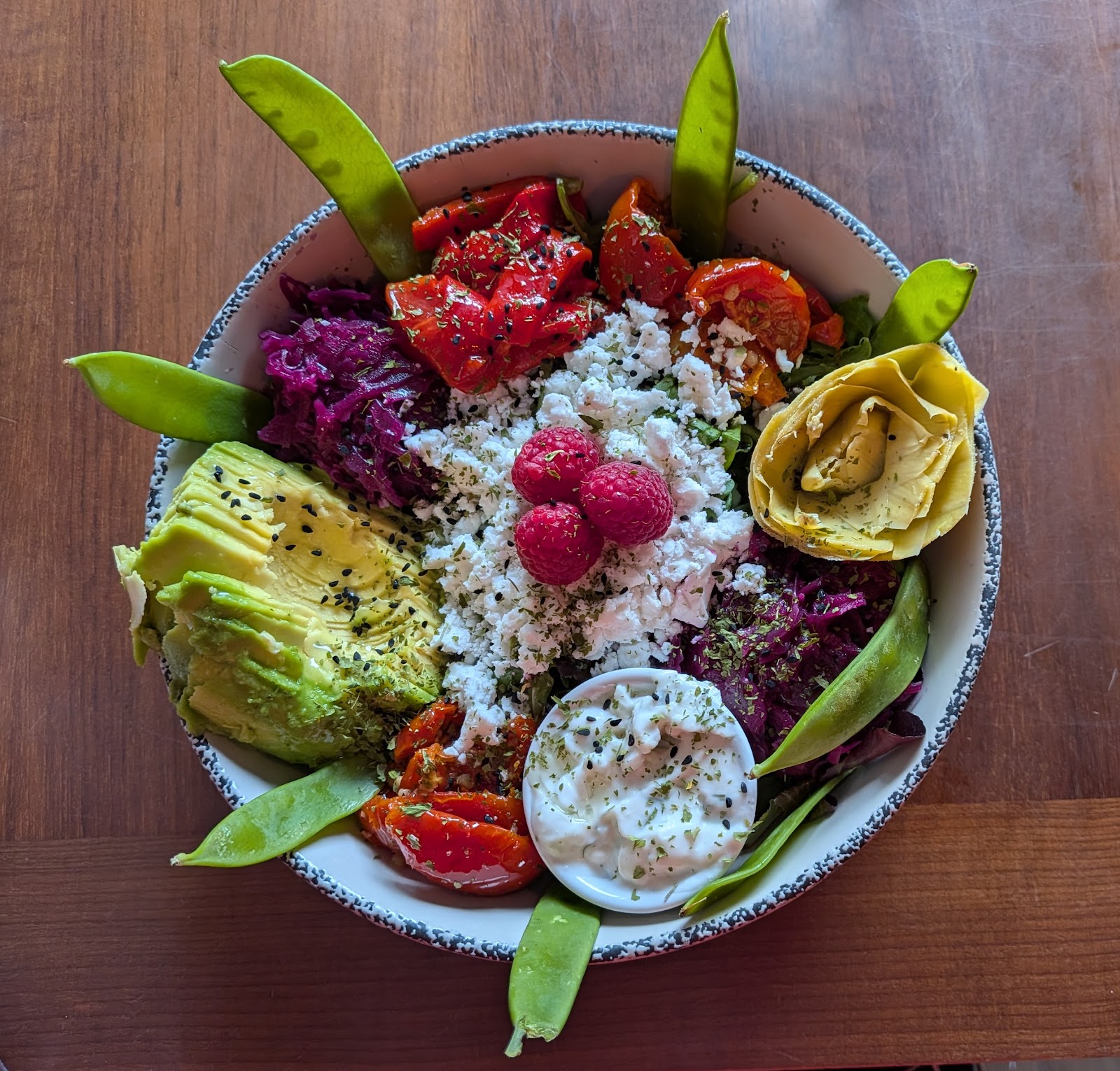 A bowl of avocado, roasted tomatoes, red cabbage, artichoke and mange tout at BioCafe, seen from above.