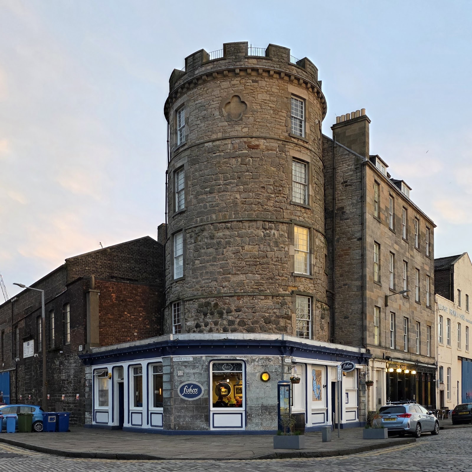 The round stone watchtower on the Shore at Leith, with Fishers' blue and white restaurant front at its foot on a cobbled corner.