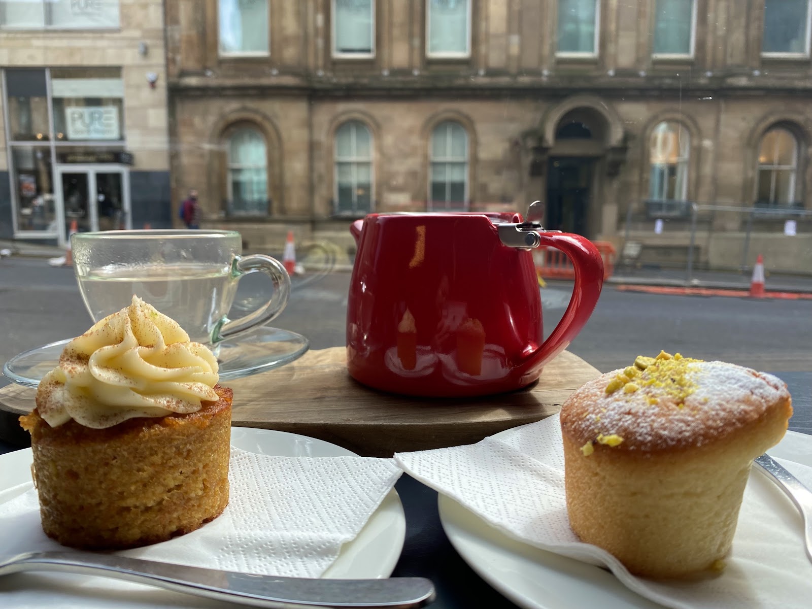 Cakes and a red teapot at a window table in Laboratorio Espresso, with the sandstone buildings of West Nile Street beyond.
