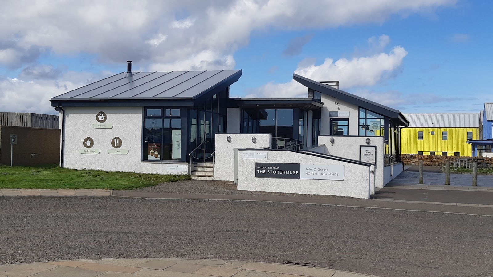 The Storehouse at John o' Groats, a modern white building with a slate roof beside the car park.