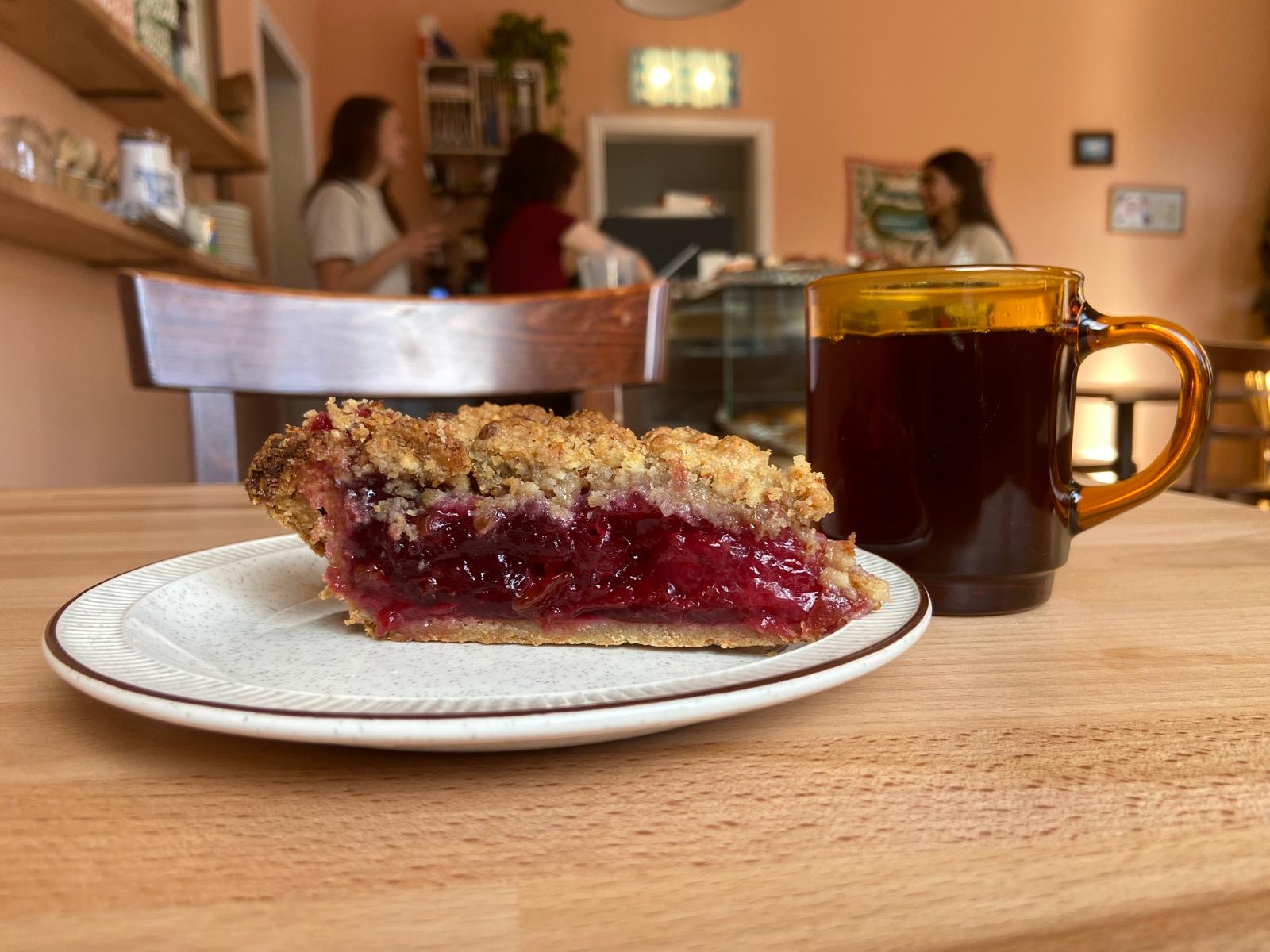 A slice of red berry crumble pie and a mug of coffee on a table at The Lea Rig on Easter Road.