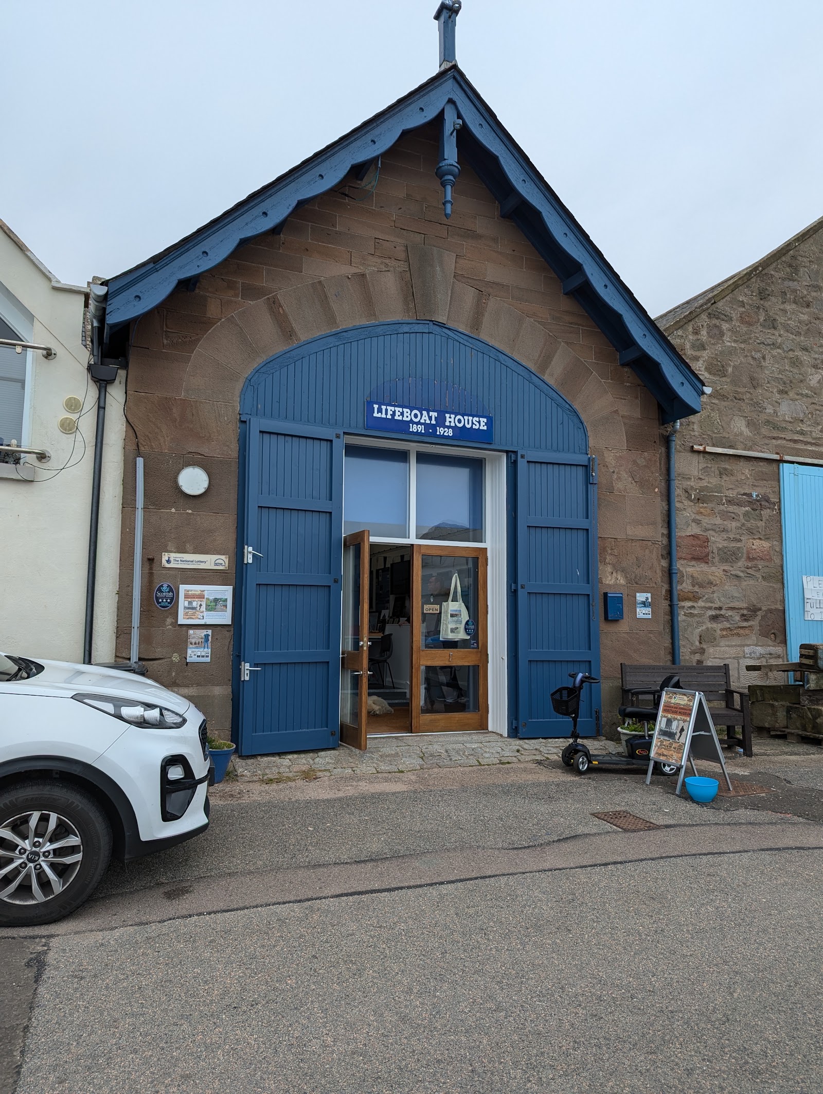 The old lifeboat house in Johnshaven, its tall blue doors open under the museum's sign.