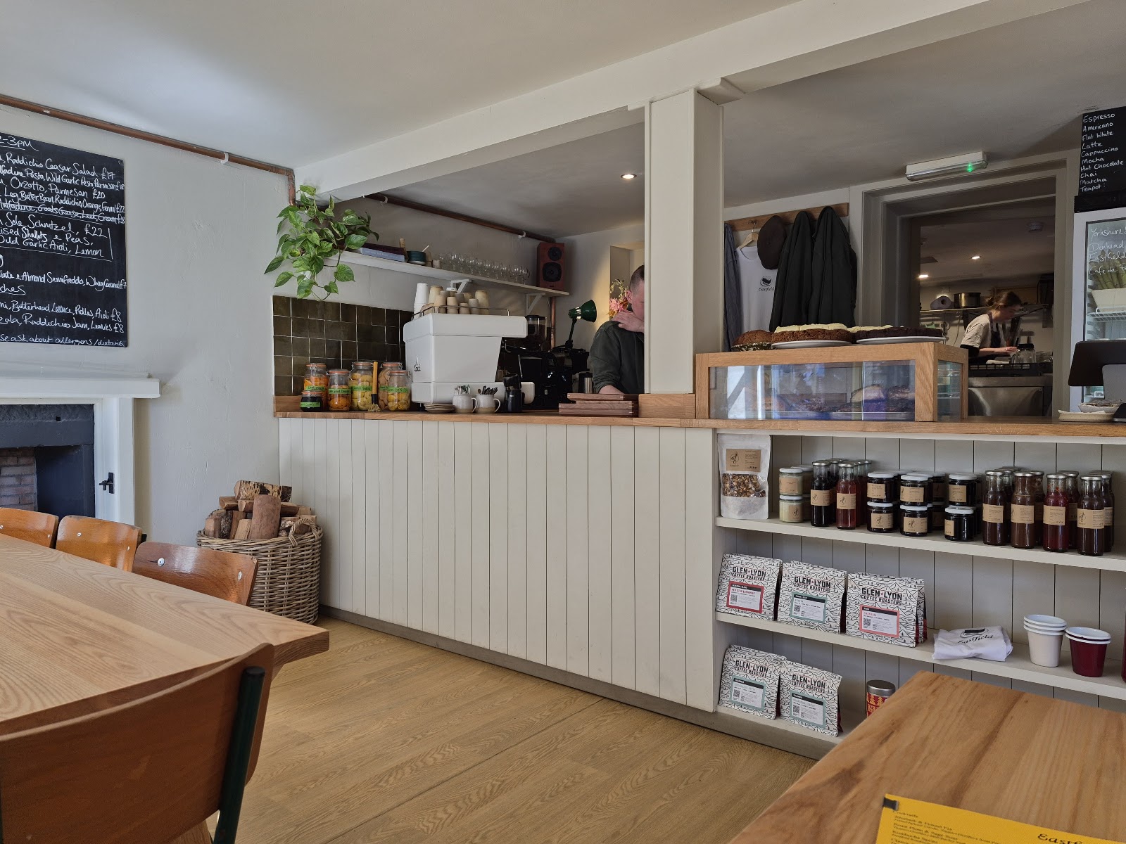 Inside Eastfield on Perth Road in Dundee: a wooden counter with the coffee machine, shelves of jars and preserves, and long wooden tables.