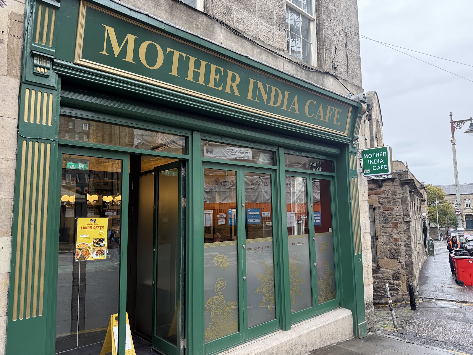 The green shopfront of Mother India Cafe on Infirmary Street in Edinburgh, its name in gold letters above the door.