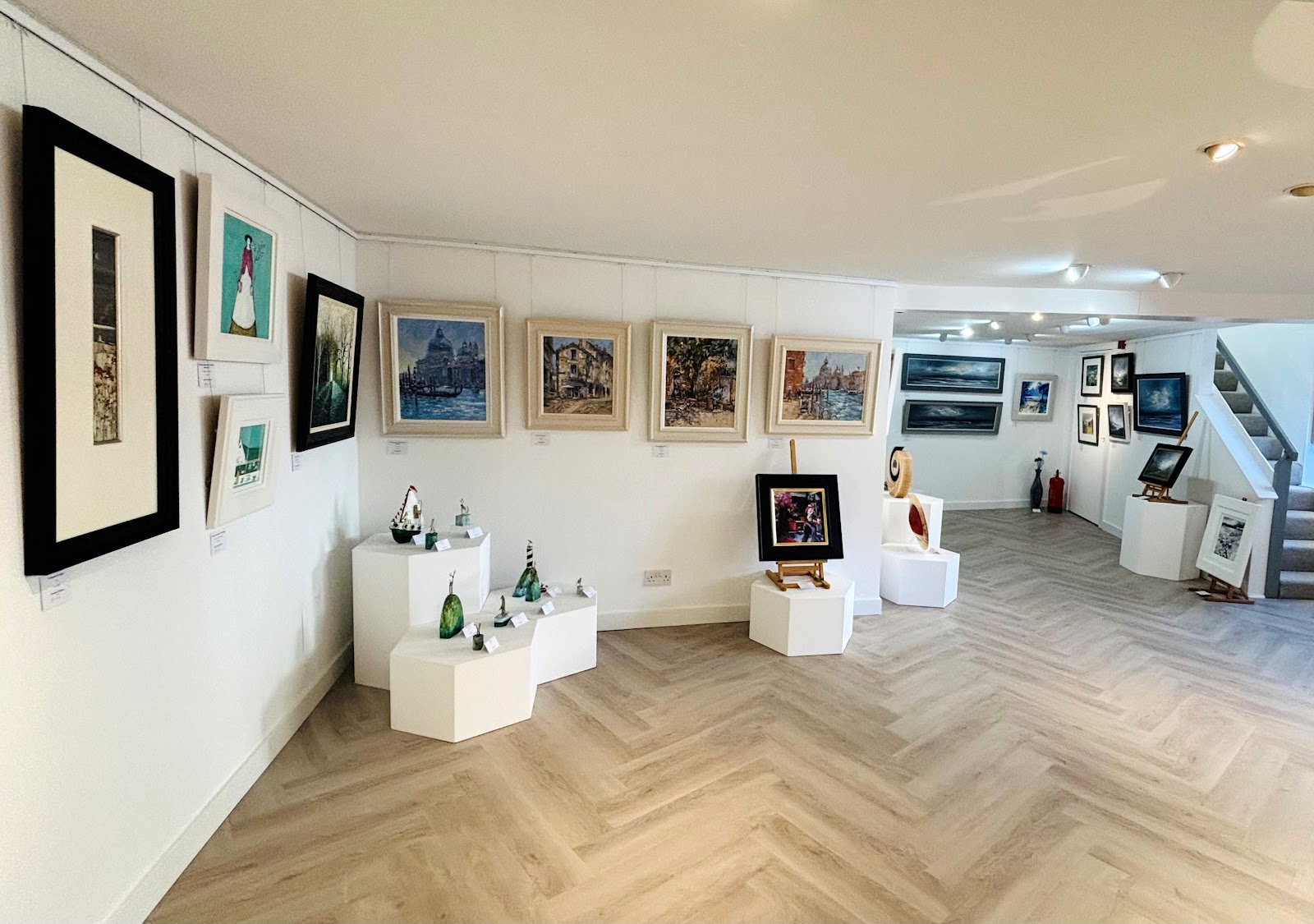 The white rooms of the Strathearn Gallery, paintings on the walls and glass and ceramics on plinths.