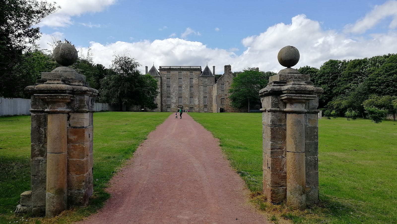 Kinneil House at the end of a red gravel avenue, seen between two stone gate piers topped with stone balls.