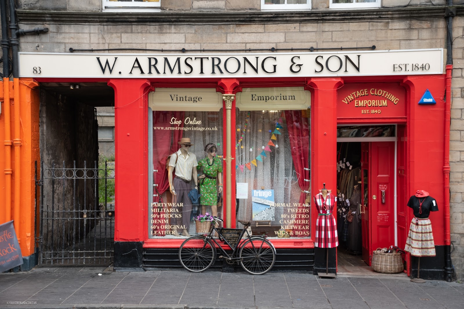 The red front of W. Armstrong & Son at 83 Grassmarket, established 1840, with a vintage bicycle and dressed mannequins outside.