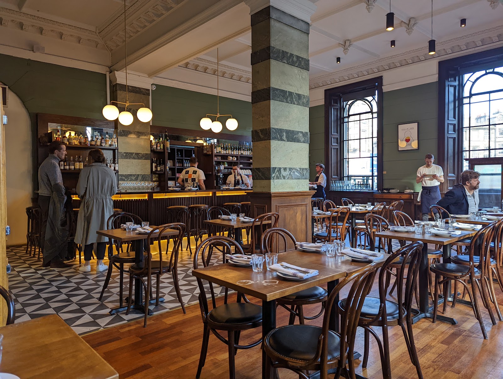 Inside the Palmerston, a high-ceilinged former bank with bentwood chairs, a patterned tiled floor by the bar, globe lights and tall arched windows.