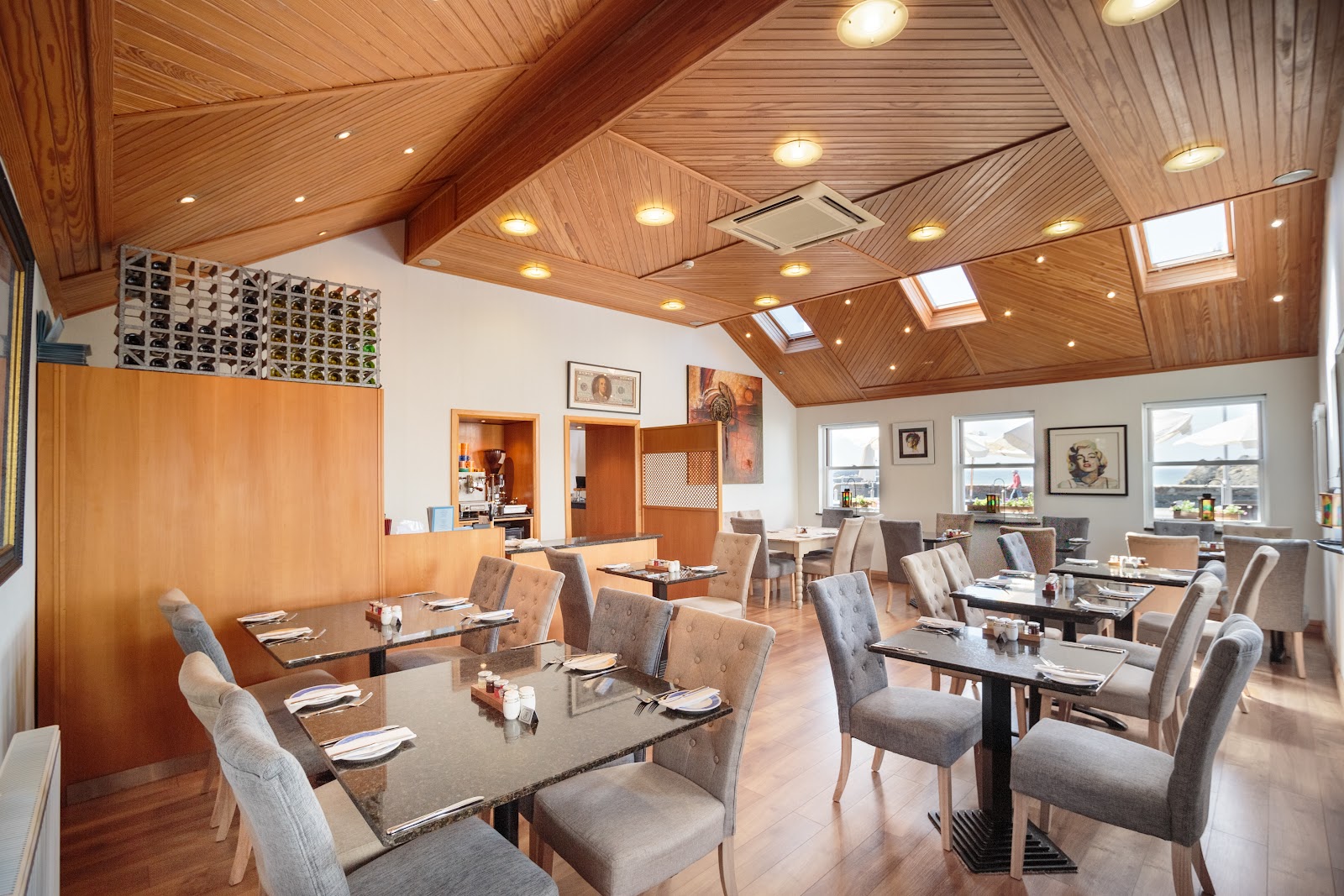 The restaurant at The Waterfront in Portpatrick, its tables laid under a pine-boarded ceiling with roof lights, and windows on the far wall.