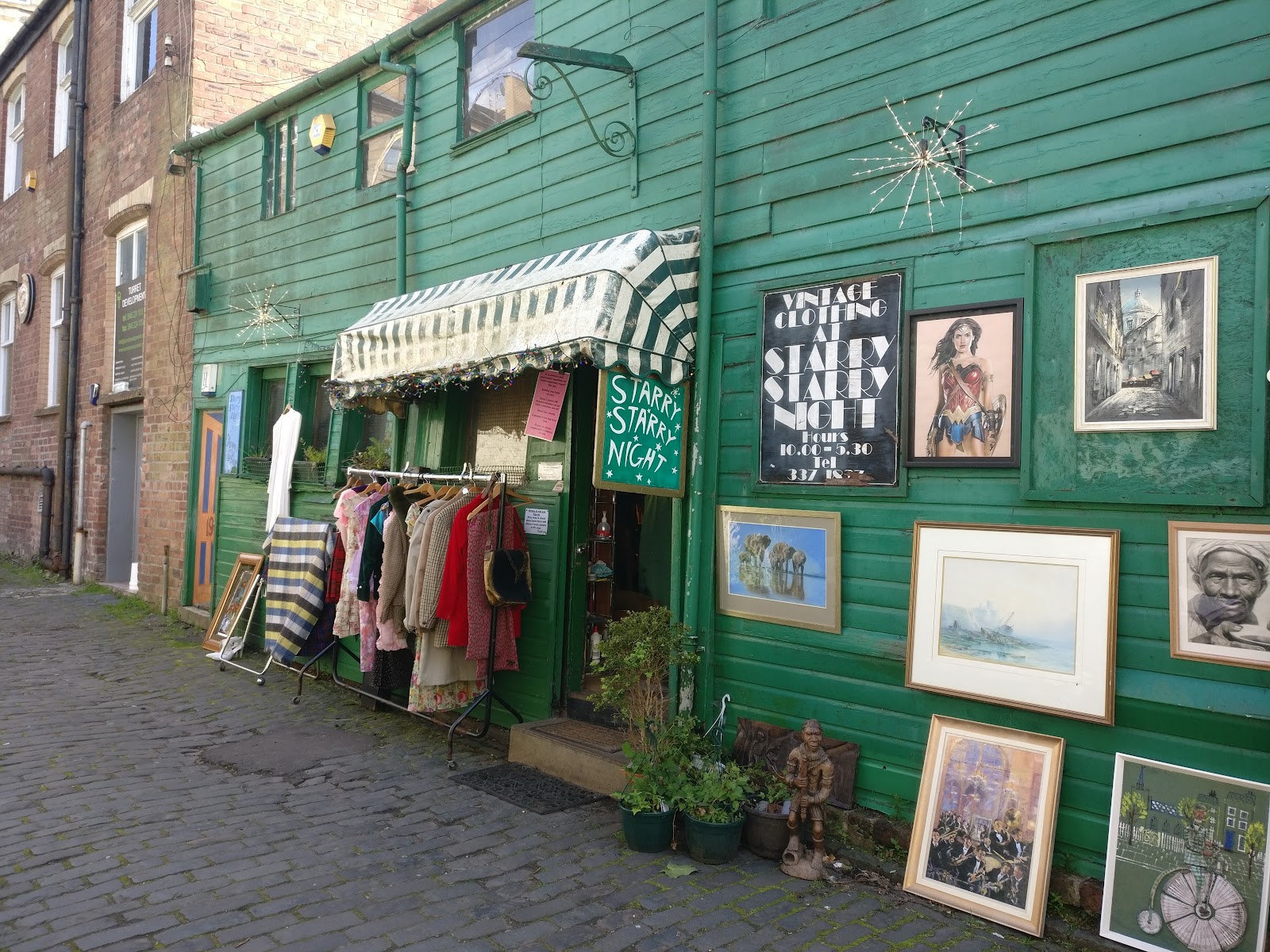 Starry Starry Night's green timber front on cobbled Dowanside Lane, with a rail of vintage clothes under a striped awning and framed pictures on the wall.