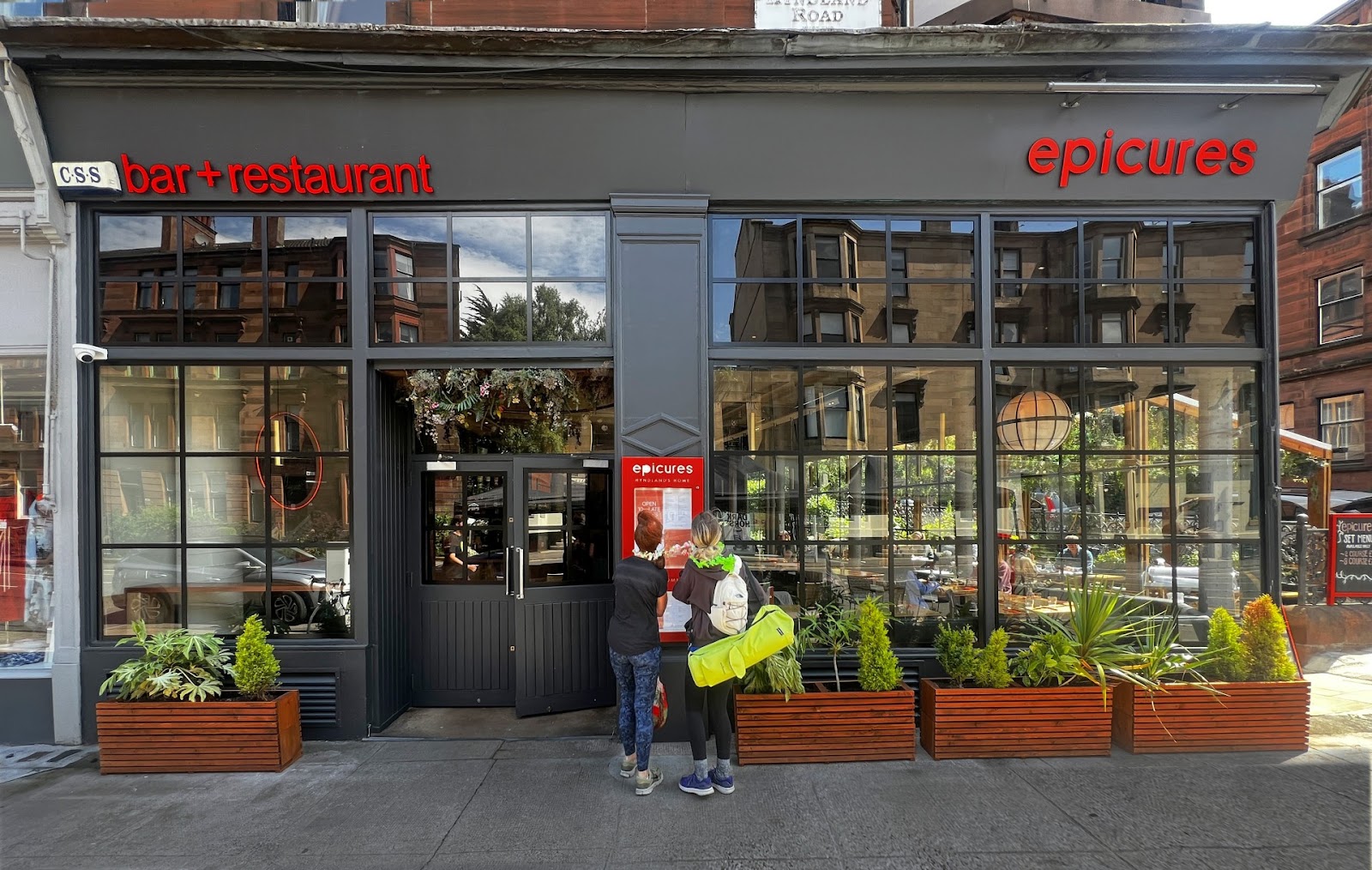 Epicures' corner front with its red sign above tall windows and planters.