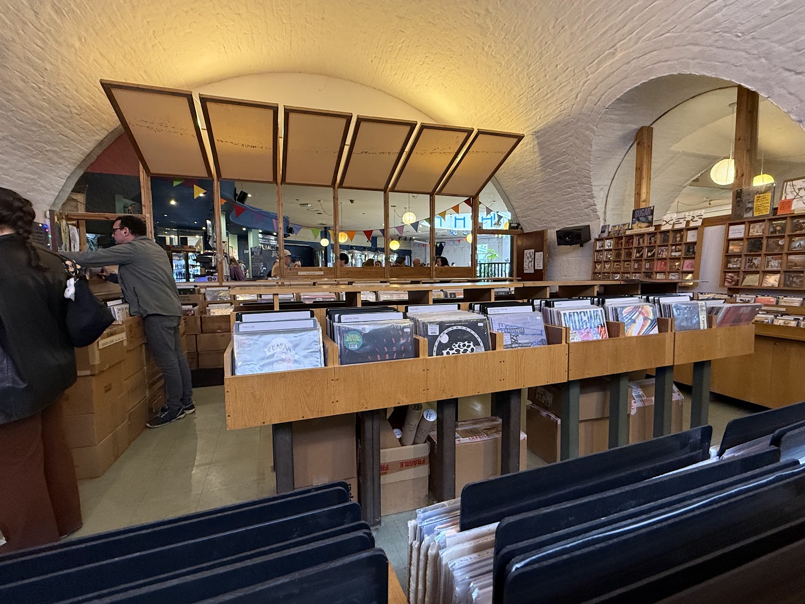 Racks of records under the white brick arches of Monorail Music, with browsers at the counter and shelves of records along the far wall.