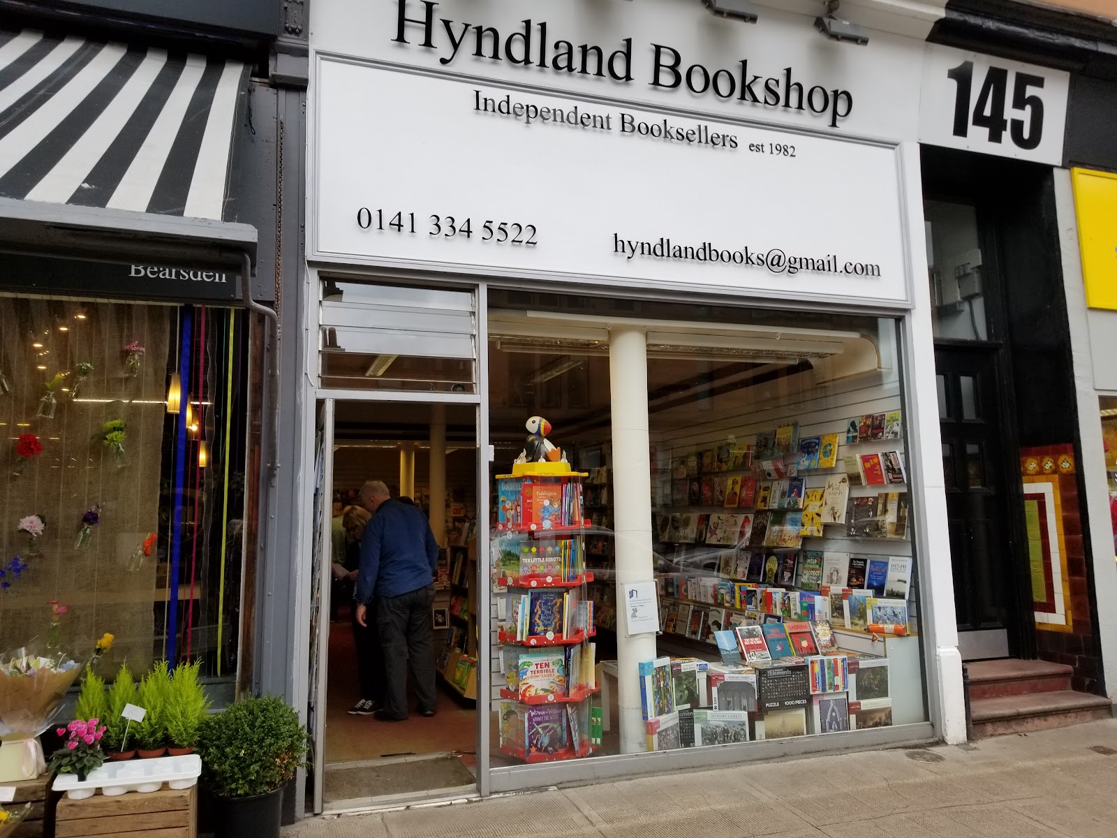 Hyndland Bookshop's white front on Hyndland Road with a striped awning next door.