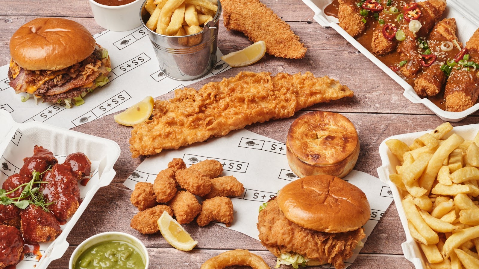 A Sea Salt + Sole spread of haddock, burgers, chicken, pies and chips on branded paper.