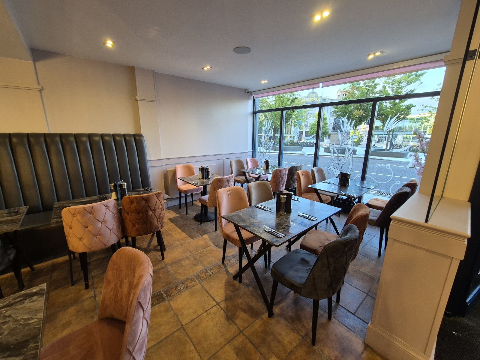The dining room of Tarragon on the Terrace, with velvet chairs, marble-topped tables and a leather banquette, and tall windows looking out to the trees of Union Terrace Gardens.