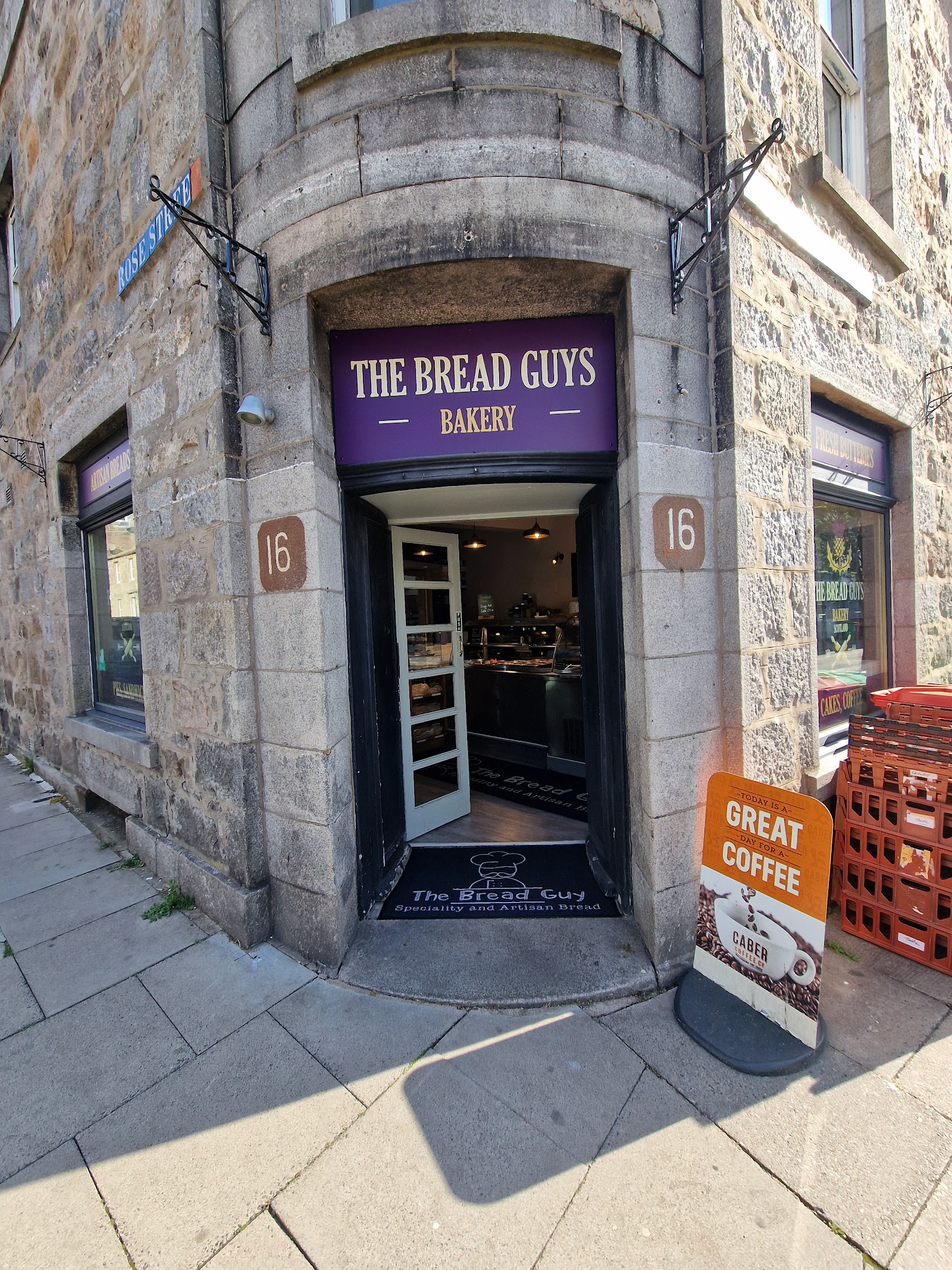 The Bread Guys Bakery at 16 Thistle Street in Aberdeen: a granite corner with a purple sign over the open door and a board outside for coffee.
